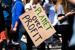 Female protester holding a "planet over profit" sign